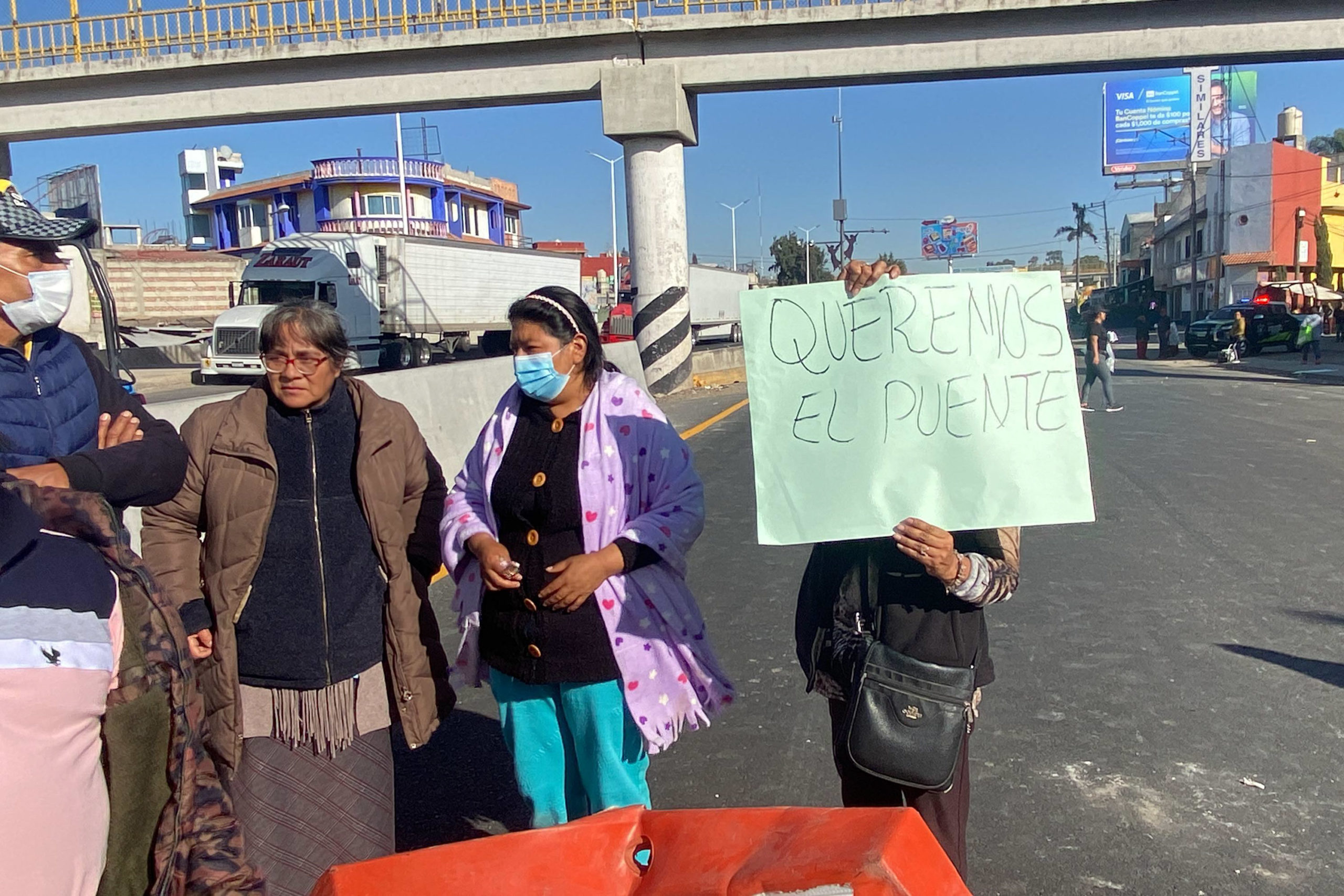 La mañana de este martes, habitantes de la colonia Seda Monsanto y usuarios del Distribuidor Vial Central de Abasto bloquearon la circulación en ambos sentidos de la Vía Corta a Santa Ana Chiautempan. Su protesta se centró en la exigencia de un puente peatonal para garantizar su seguridad.  Los manifestantes explicaron que el puente peatonal que existía en la zona fue retirado al iniciar las obras del distribuidor vial, inaugurado el pasado 14 de octubre. Desde entonces, afirman, cruzar la carretera se ha convertido en una actividad peligrosa debido a las altas velocidades de los vehículos.  El bloqueo, que comenzó alrededor de las 8:00 horas, provocó un intenso tráfico vehicular que se reportó en redes sociales poco después de iniciada la protesta. Elementos de Tránsito Municipal acudieron al lugar para mediar, aunque no se registraron acercamientos con autoridades responsables de la obra para atender la demanda de los ciudadanos.  Desde su apertura, usuarios del distribuidor han señalado la falta de infraestructura peatonal, como semáforos o topes. Los vecinos subrayaron que esta omisión compromete la seguridad de quienes transitan diariamente por la zona y exigieron una pronta respuesta para solucionar el problema.