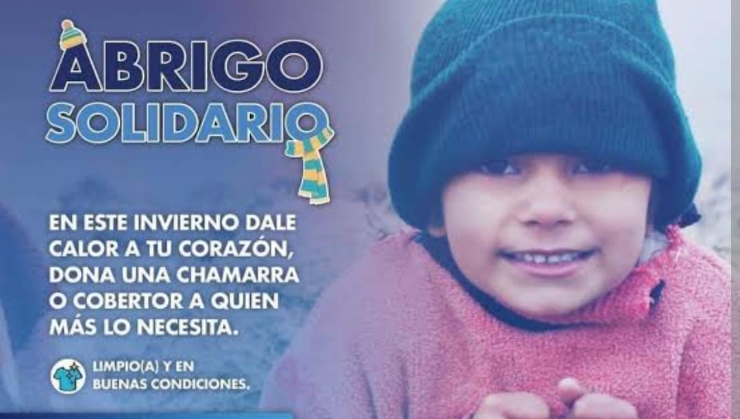 Mantiene los brazos extendidos “Abrigo Solidario” para recibir chamaras y suéteres destinados a personas vulnerables